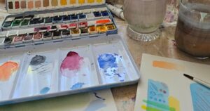 Mein kreativer Arbeitsplatz mit Aquarellfarben, Pinsel und Übungsblatt