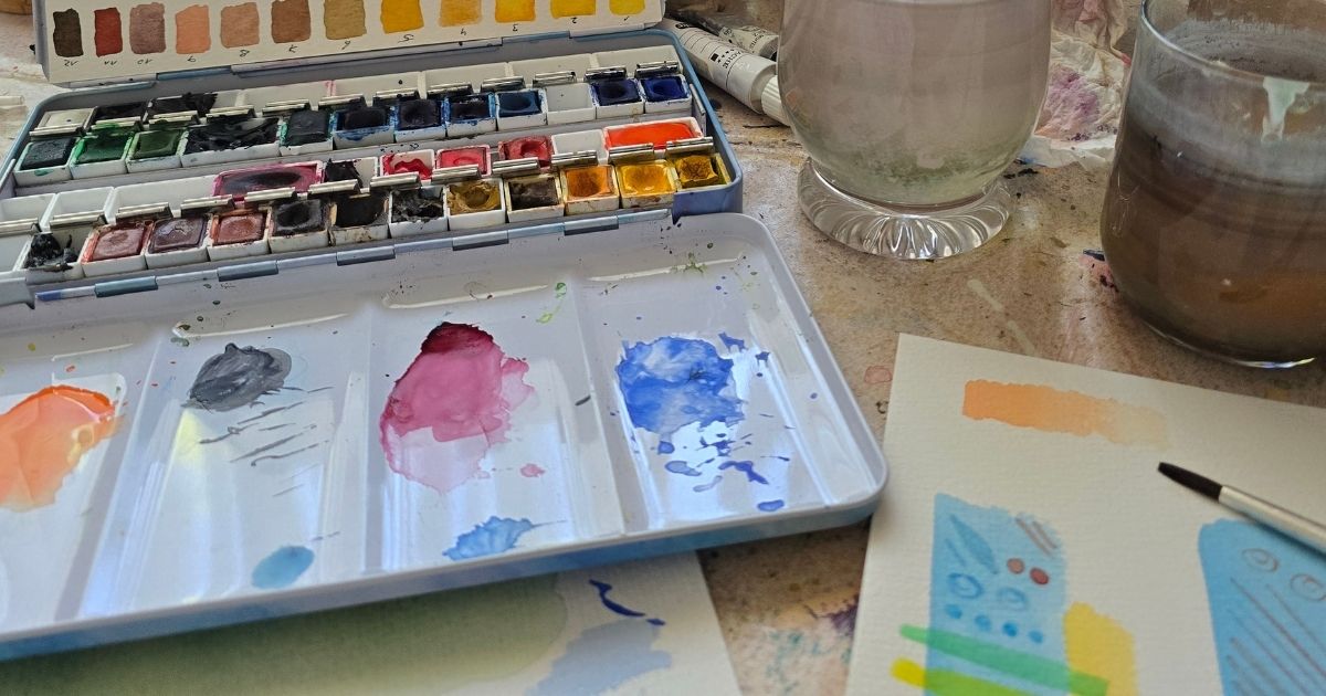 Mein kreativer Arbeitsplatz mit Aquarellfarben, Pinsel und Übungsblatt